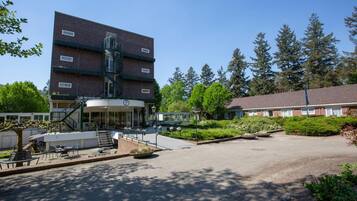 A building with a brick facade, a covered entrance, and a landscaped courtyard with outdoor seating.