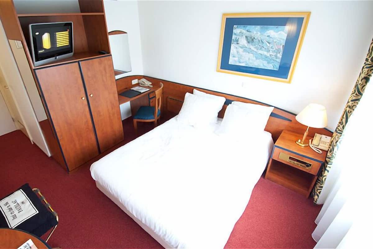 Ein Hotelzimmer mit Bett, Schreibtisch und Kleiderschrank.