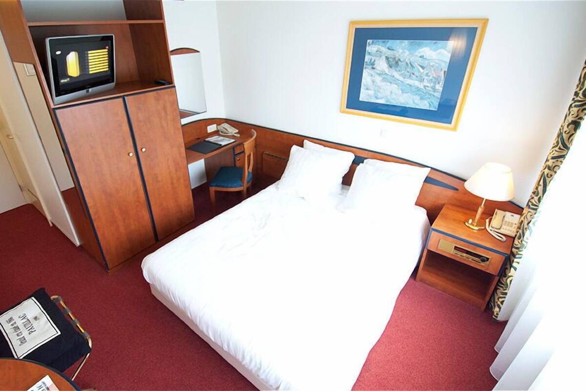 A hotel room with a bed, desk, and wardrobe.