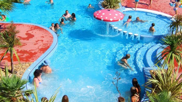 Ein großer Außenpool mit mehreren Wasserspielen und Palmen.