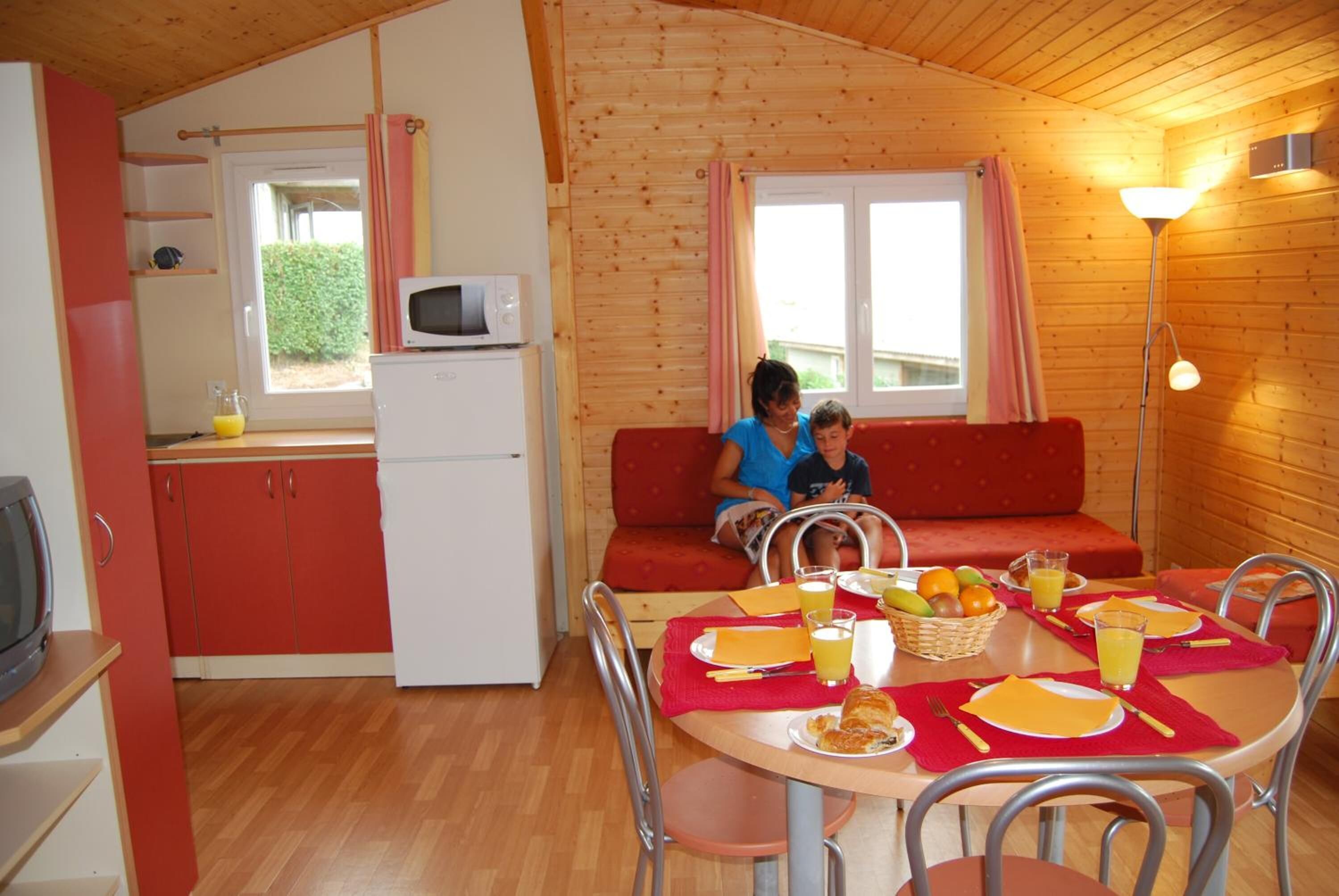 Un chalet confortable avec un coin repas, une cuisine et un canapé.