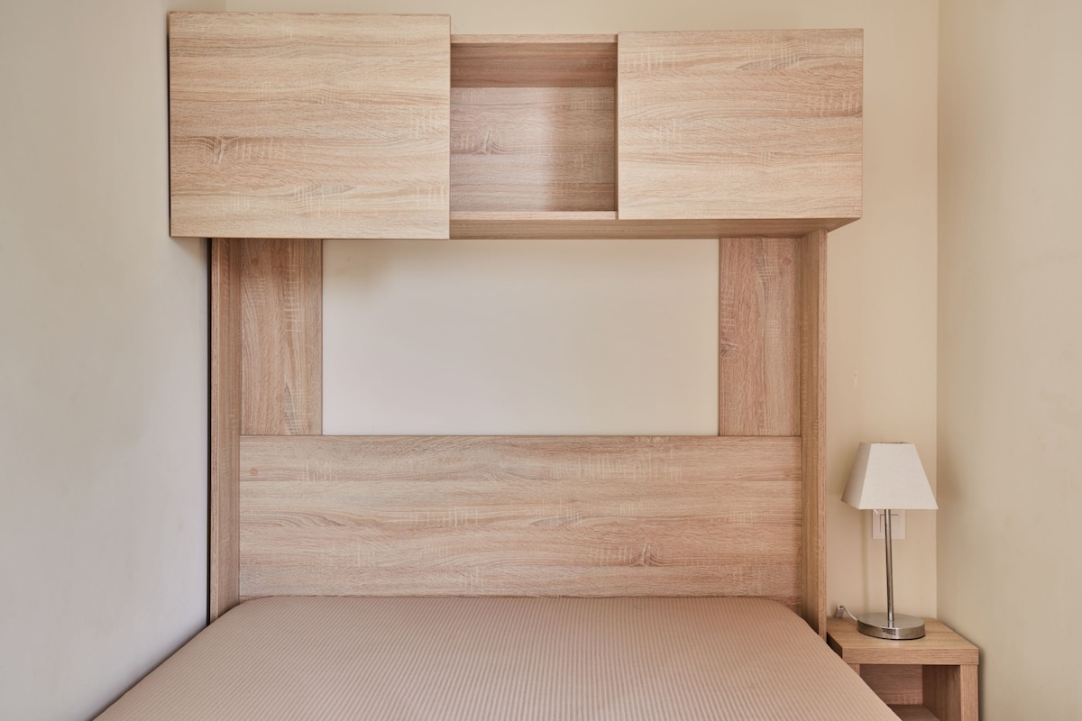 A bed with a wooden headboard and a bedside table with a lamp.