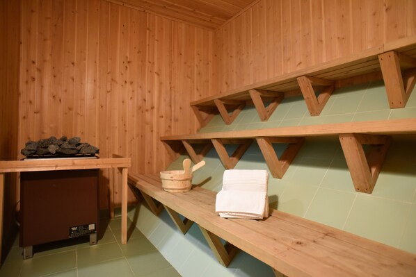 Una sauna de madera con bancos, un balde de madera y una toalla.