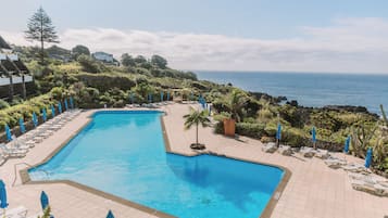Una piscina al aire libre, sombrillas, sillones reclinables de piscina