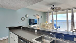 Una cocina moderna con una isla central, dos fregaderos y un comedor con vista al océano.