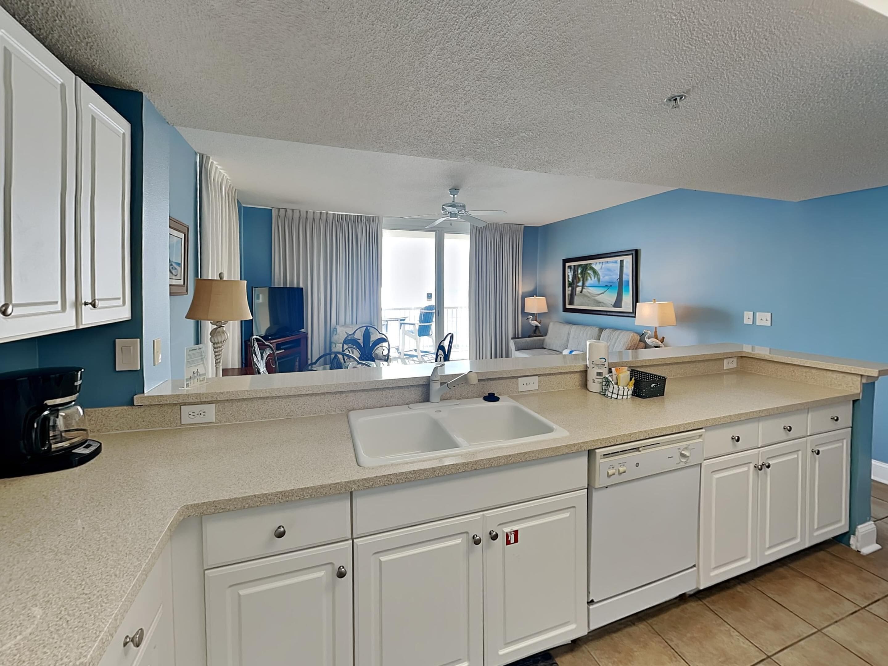 A modern kitchen with white cabinets, a large sink, and a countertop with a coffee maker.