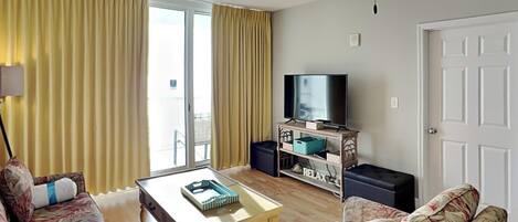 A living room with a sofa, a coffee table, a television, and a ceiling fan.