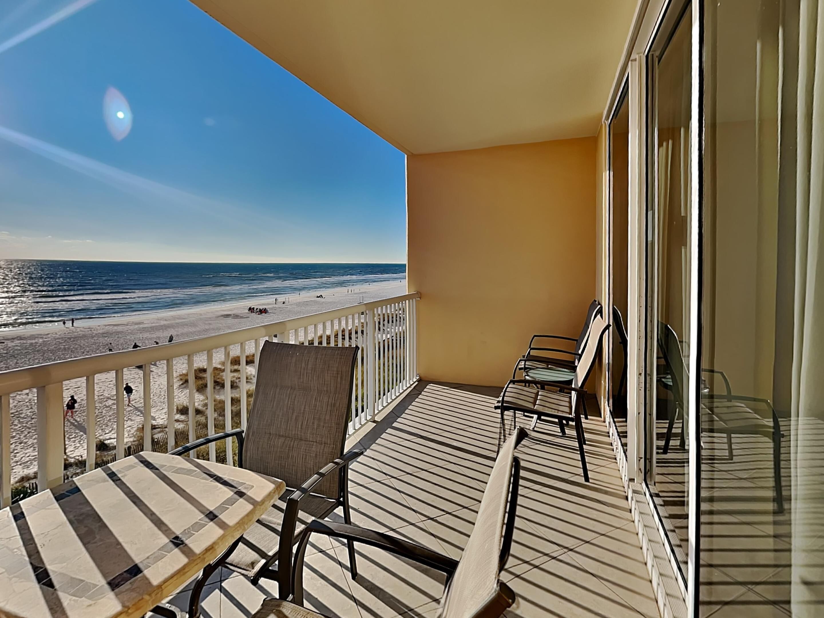 Un balcon avec vue sur la plage, une table et deux chaises.