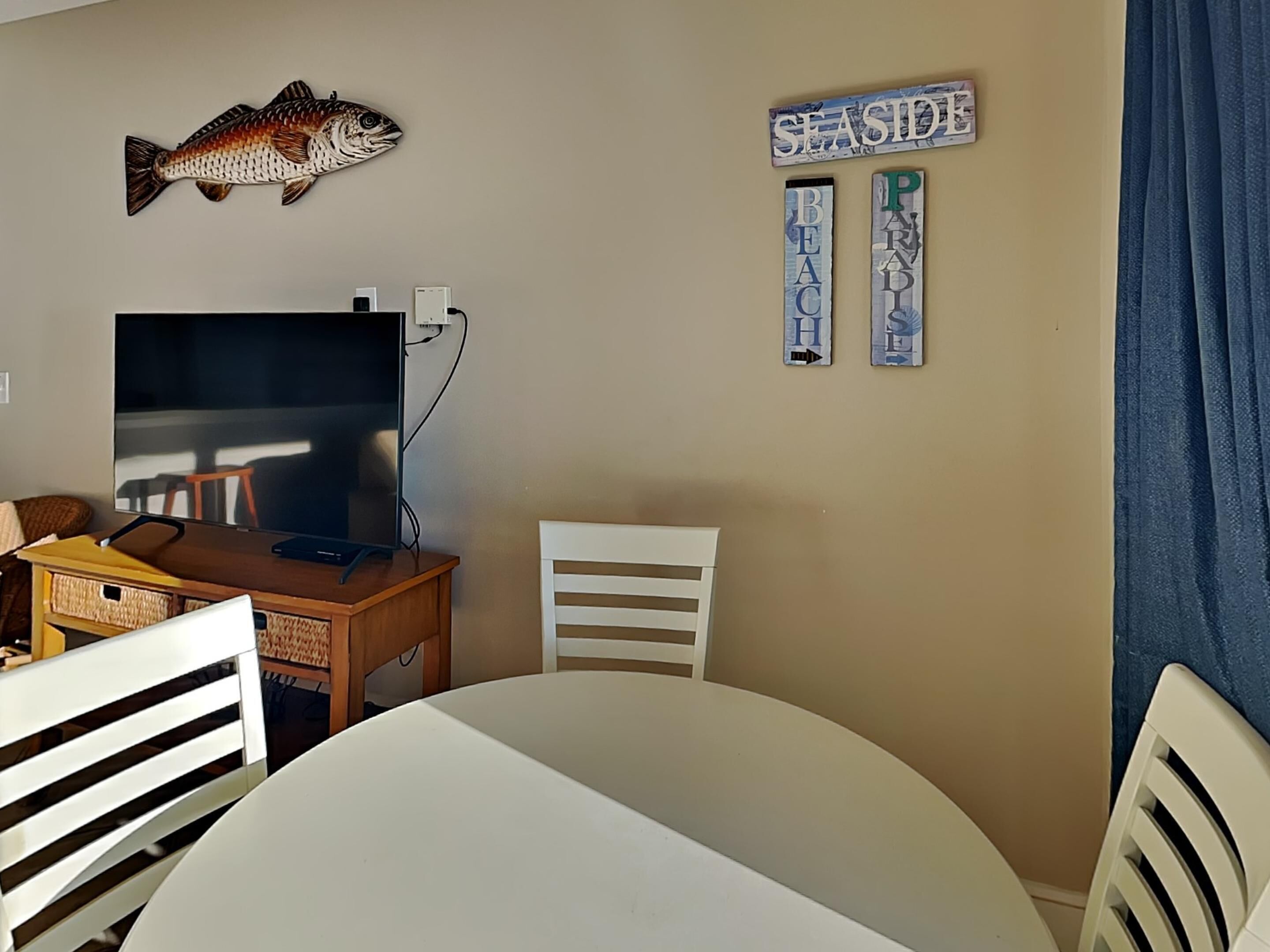 A room with a television, a fish decoration, and a 'SEASIDE' sign on the wall.