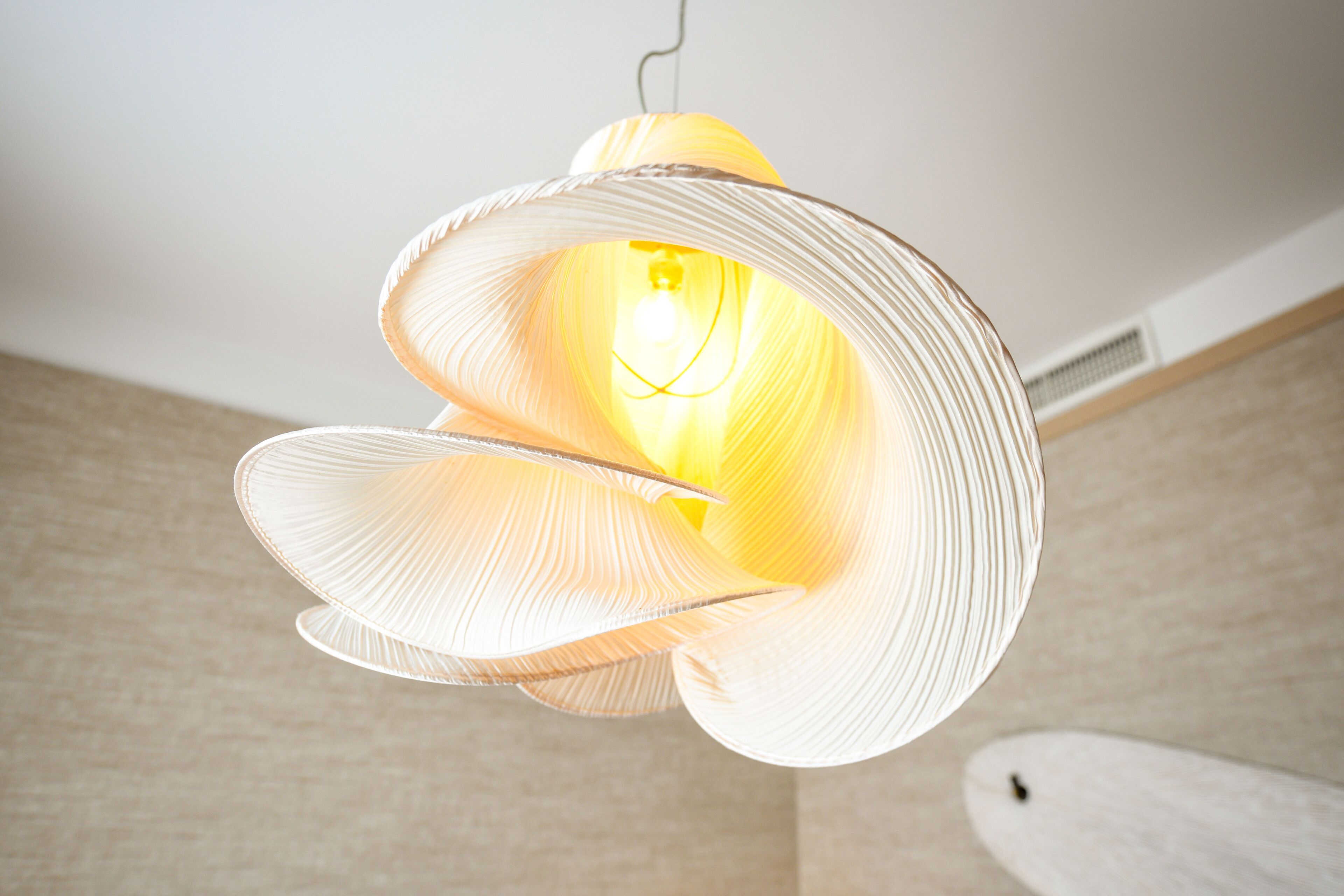A modern, abstract light fixture with a central bulb, suspended from the ceiling.