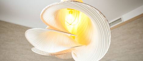 A modern, abstract light fixture with a central bulb, suspended from the ceiling.