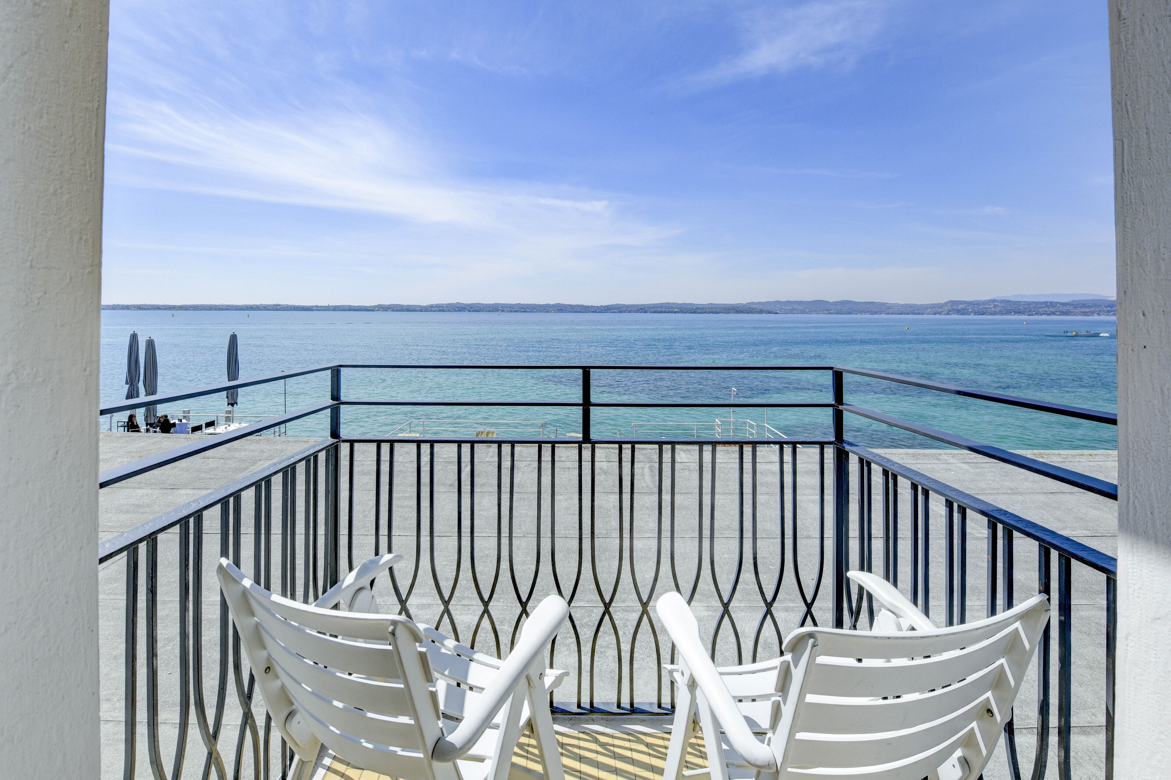 A balcony with white chairs overlooking a body of water.