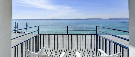 A balcony with white chairs overlooking a body of water.