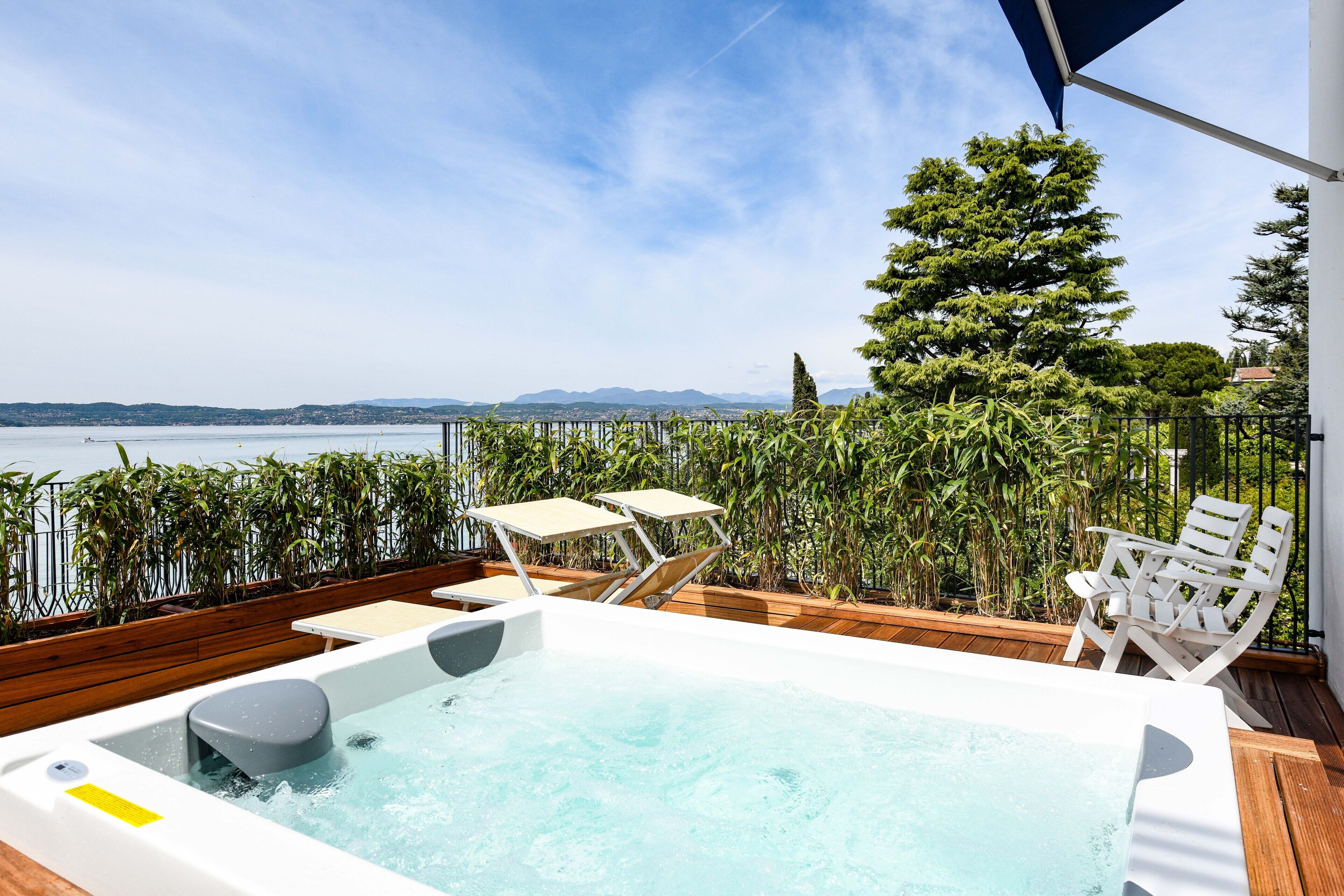 A hot tub on a wooden deck with a view of the sea and mountains.
