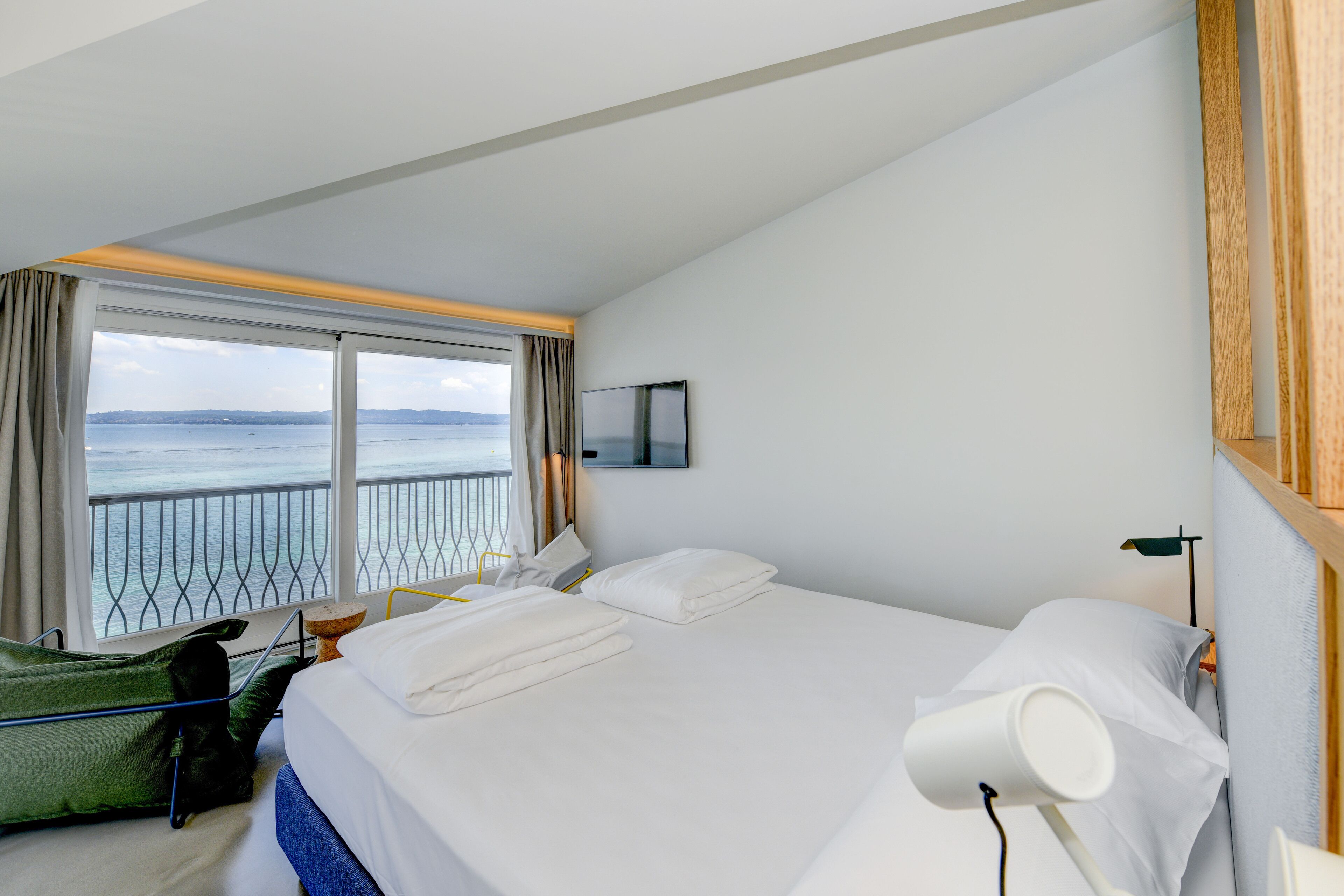 Habitación de hotel con una cama grande, vista al mar, una mesita y una silla.
