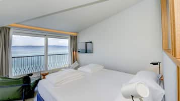 Ein Hotelzimmer mit einem großen Bett, Meerblick, einem kleinen Tisch und einem Stuhl.