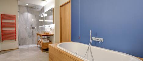 A modern bathroom with a freestanding bathtub, a glass shower enclosure, and a wooden vanity.