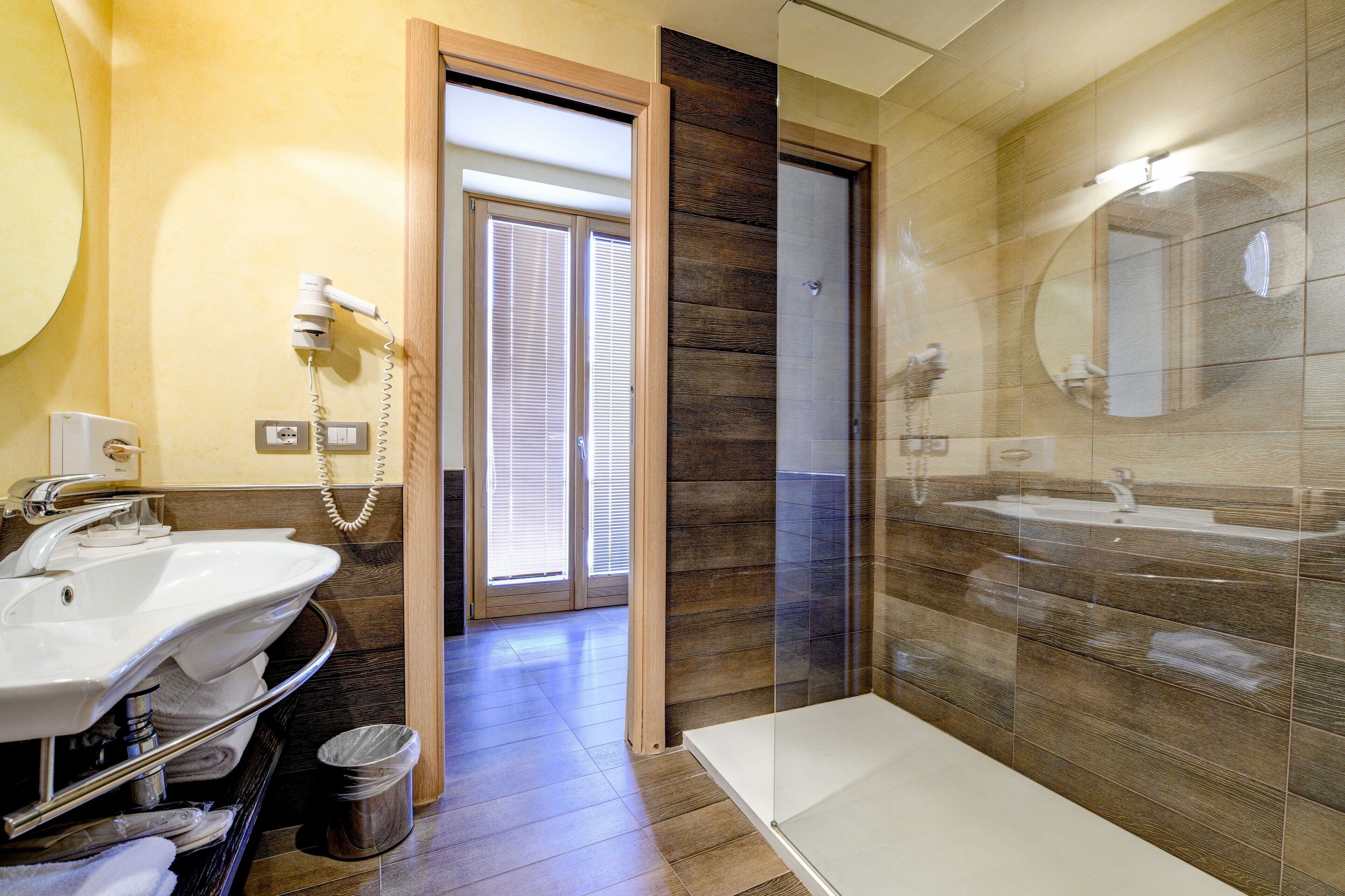 Un baño moderno con un espejo grande, dos lavamanos y una zona de ducha.