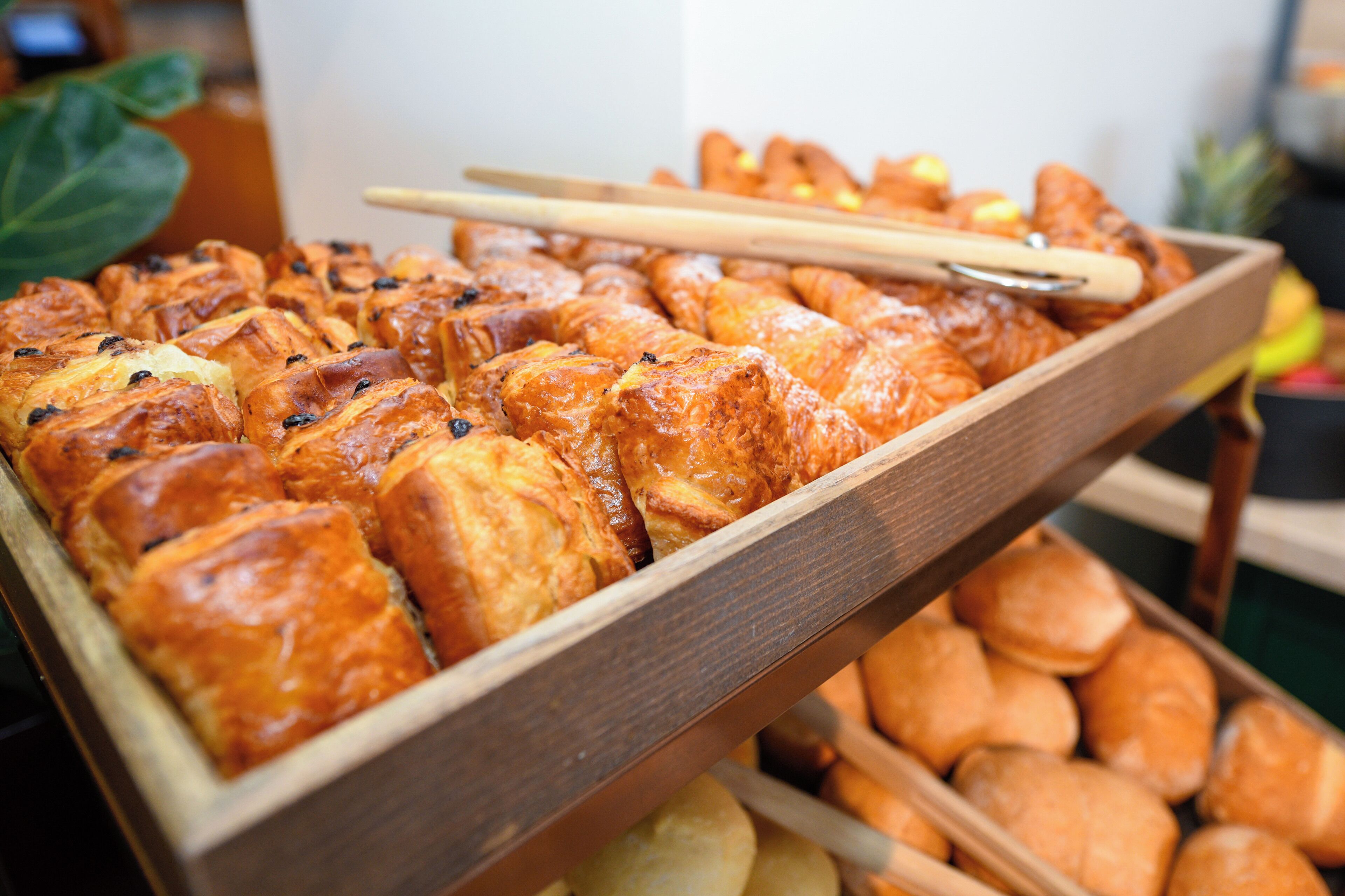 A wooden tray filled with various baked goods, including pastries and bread.