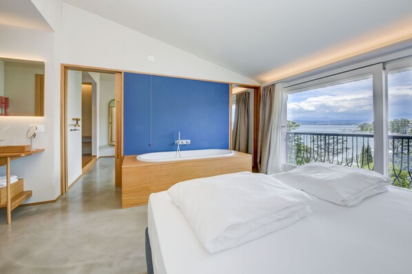 A modern hotel room with a large bed, a bathtub, and a balcony with a view of the sea. - Hotel Flaminia (Sirmione)