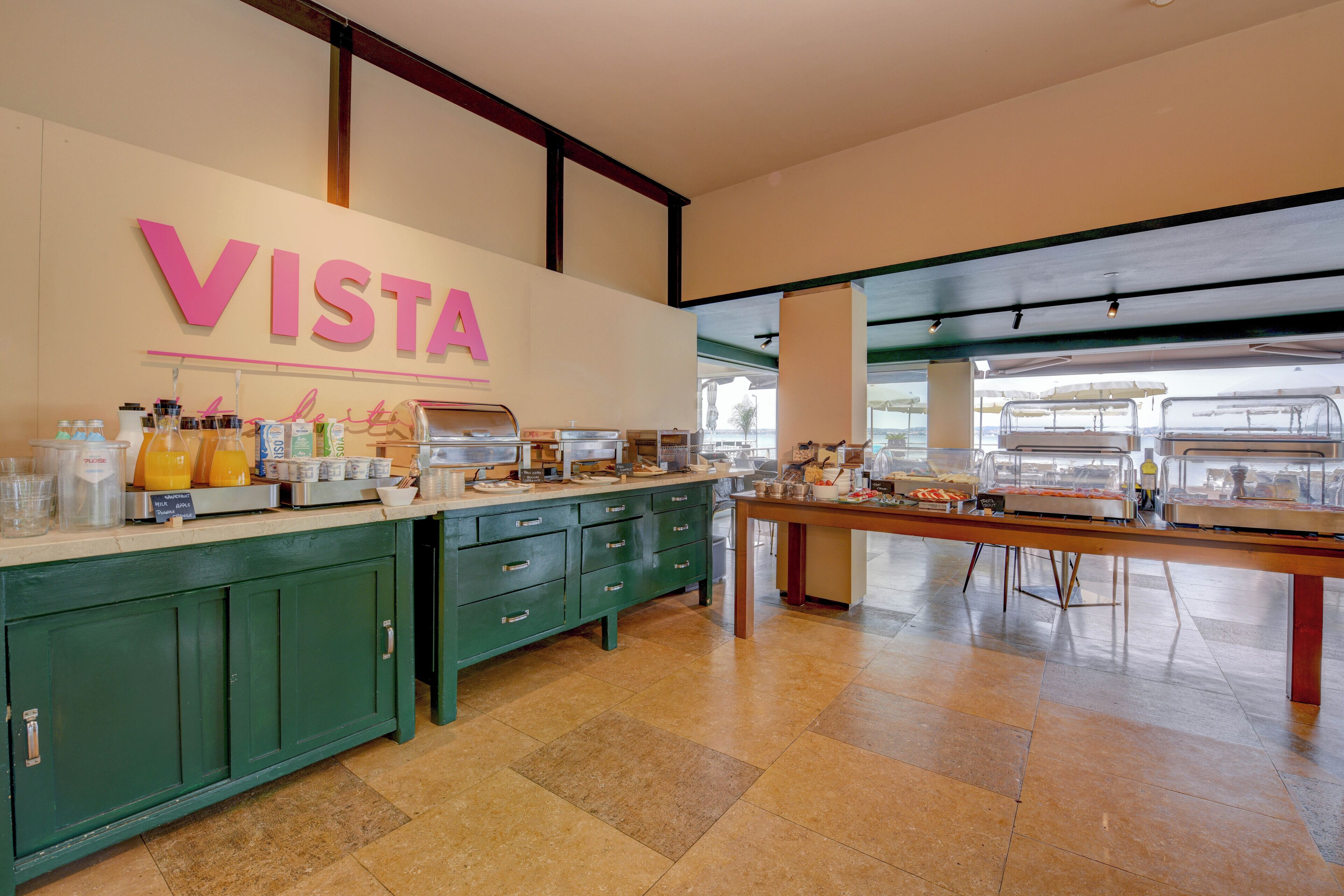 A breakfast area with a counter displaying various food items and a sign that reads "VISTA".