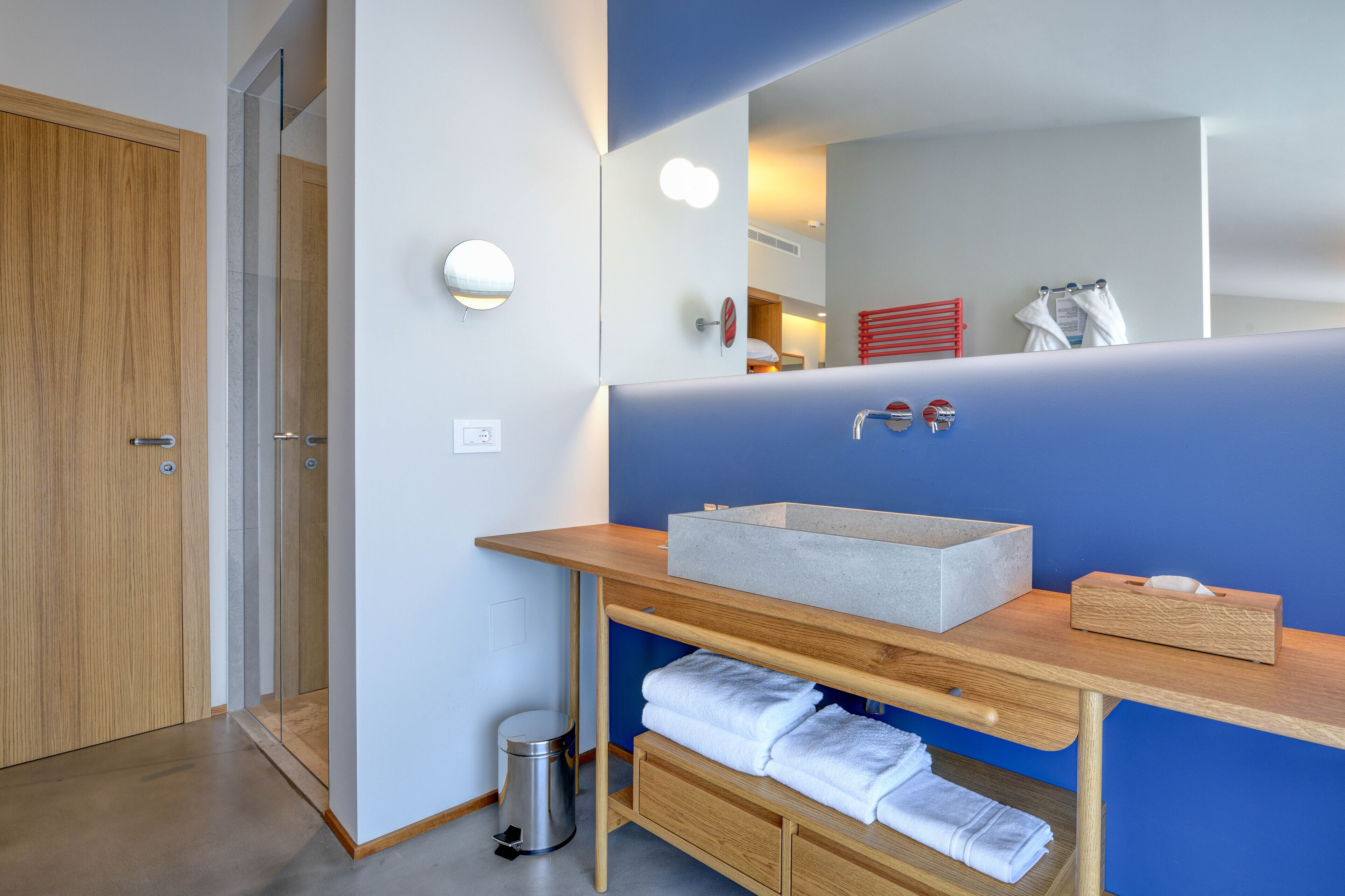 Un bagno moderno con un mobile vanitario in legno, uno specchio grande e una parete decorata in blu.