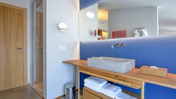 Un bagno moderno con un mobile vanitario in legno, uno specchio grande e una parete decorata in blu.