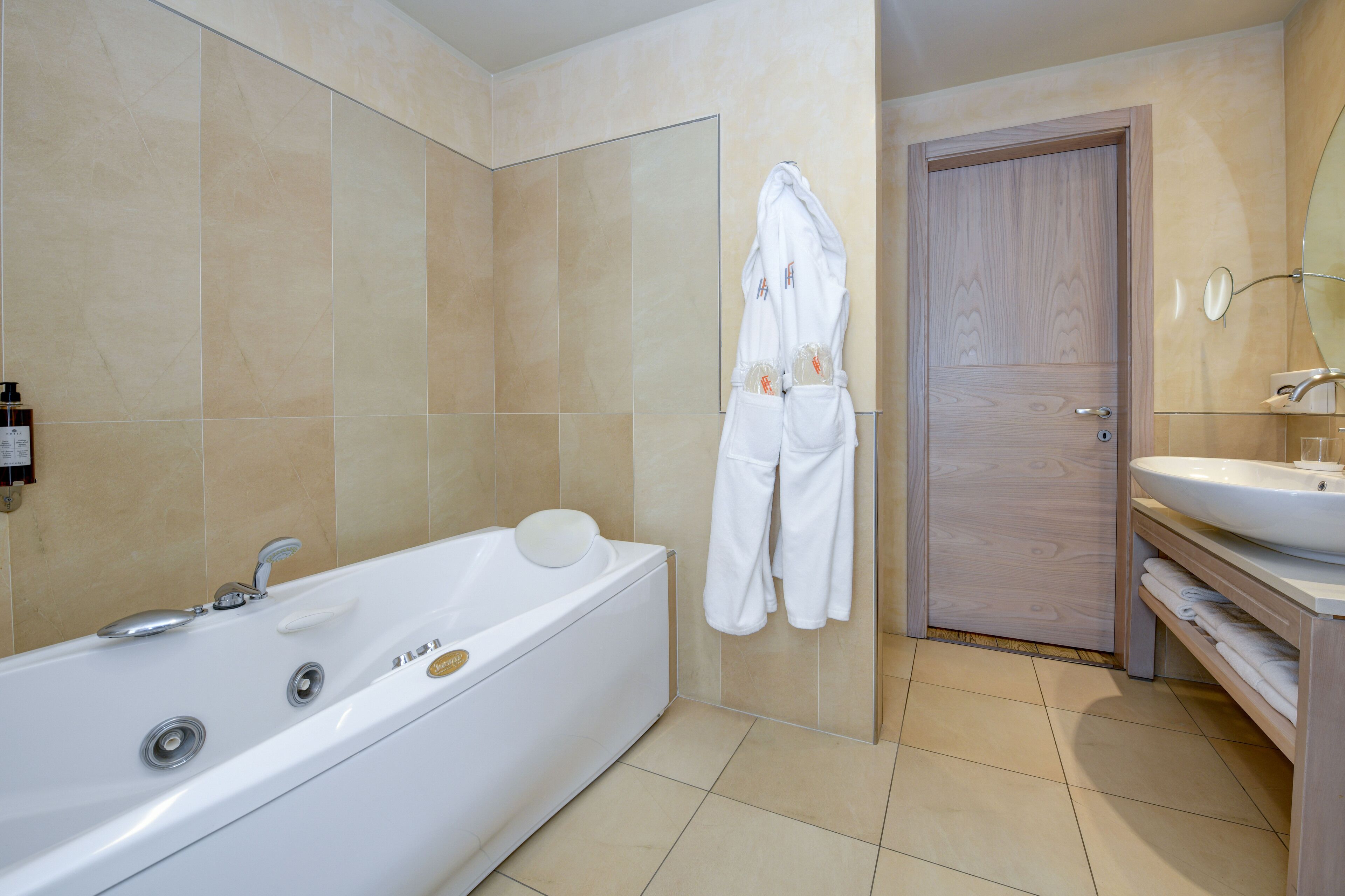Un bagno moderno con una vasca da bagno ampia, una porta in legno e un lavandino bianco.