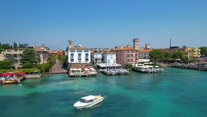 A waterfront area with a boat dock, buildings, and a pier with umbrellas. - Hotel Flaminia (Sirmione)