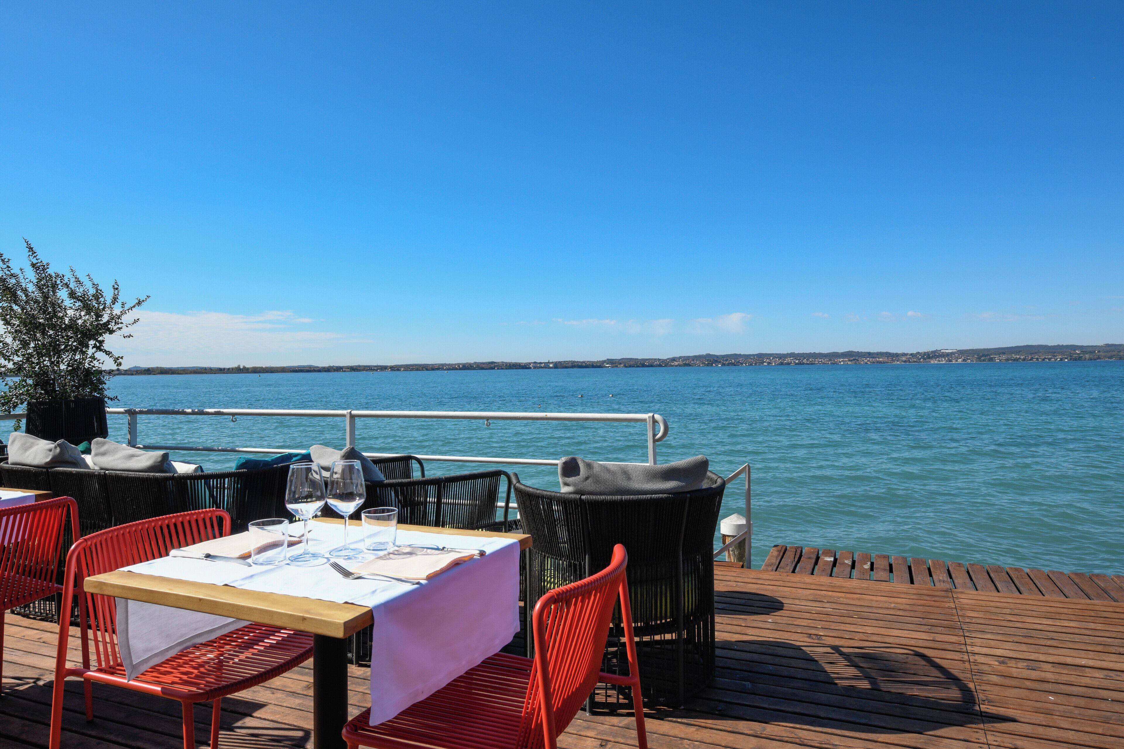 Un comedor con una mesa preparada para dos personas, con vista a un cuerpo de agua.