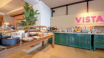 Un espace buffet proposant une variété de plats, une grande plante et un panneau indiquant le mot « VISTA ».