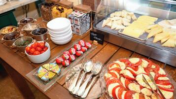 Un bufé con diversos alimentos, incluyendo queso, tomates y una variedad de otros platos.