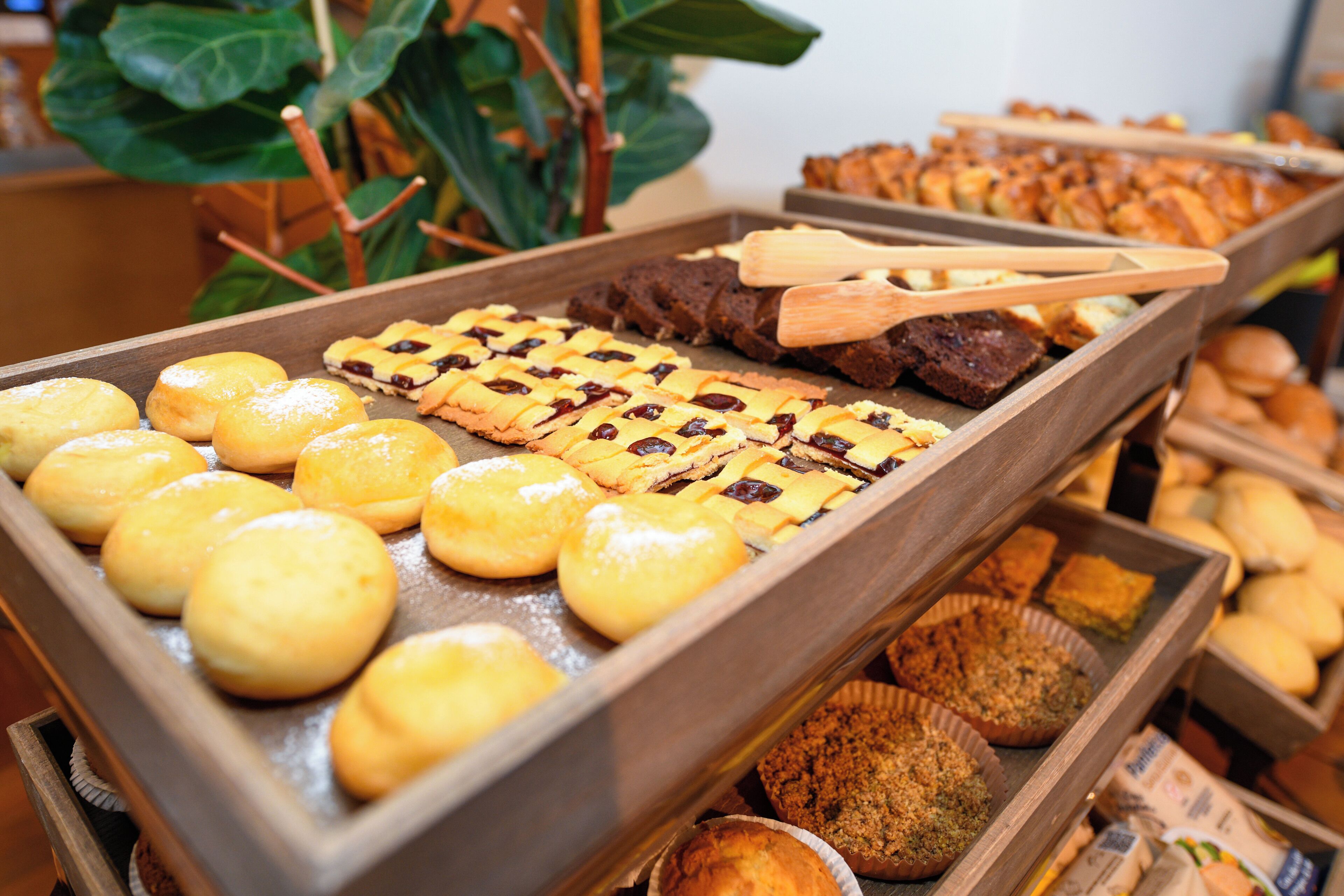 Diversas opciones de productos horneados expuestas en bandejas de madera, como muffins, galletas y brownies.