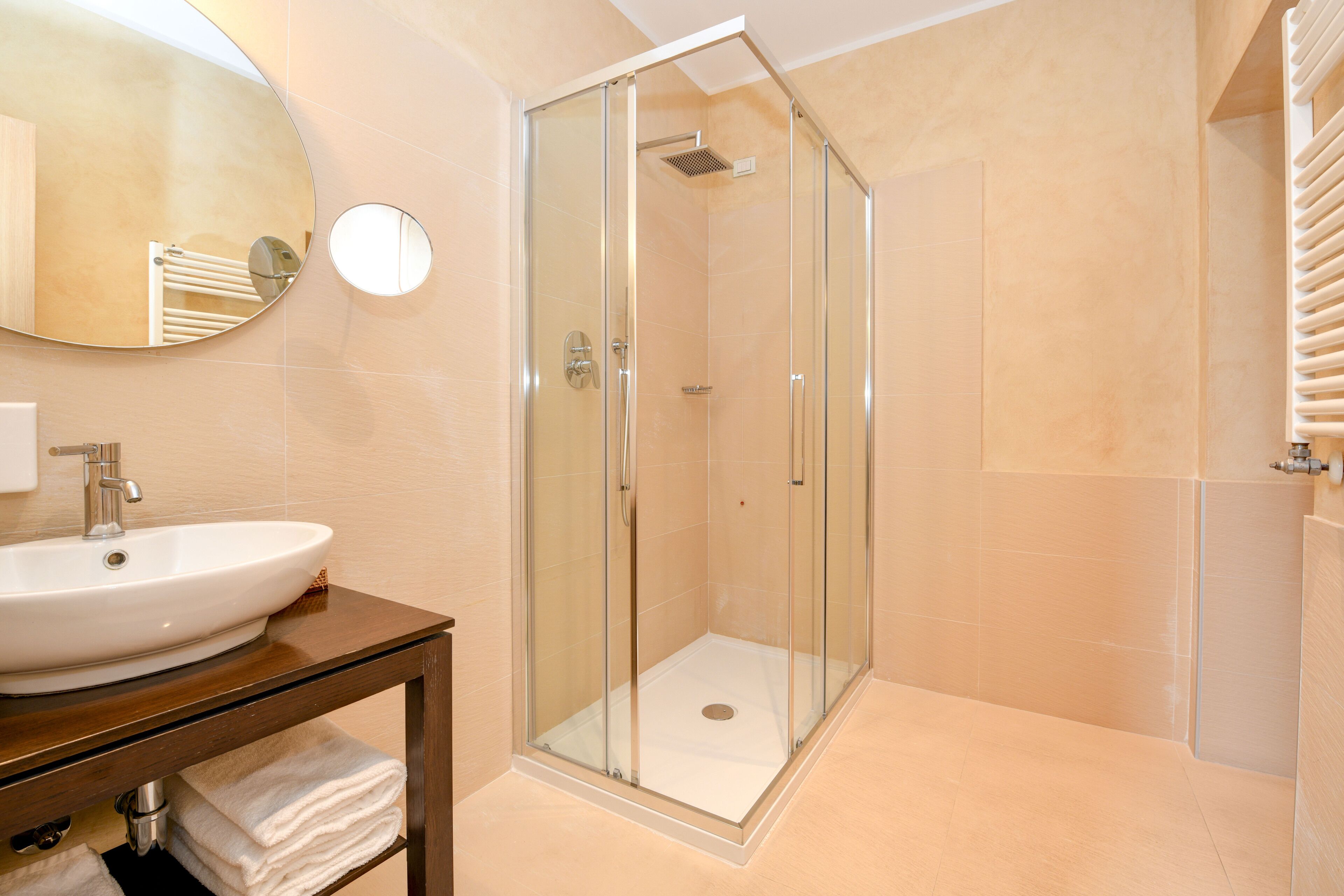 Un baño moderno con ducha de vidrio, lavamanos y espejo.