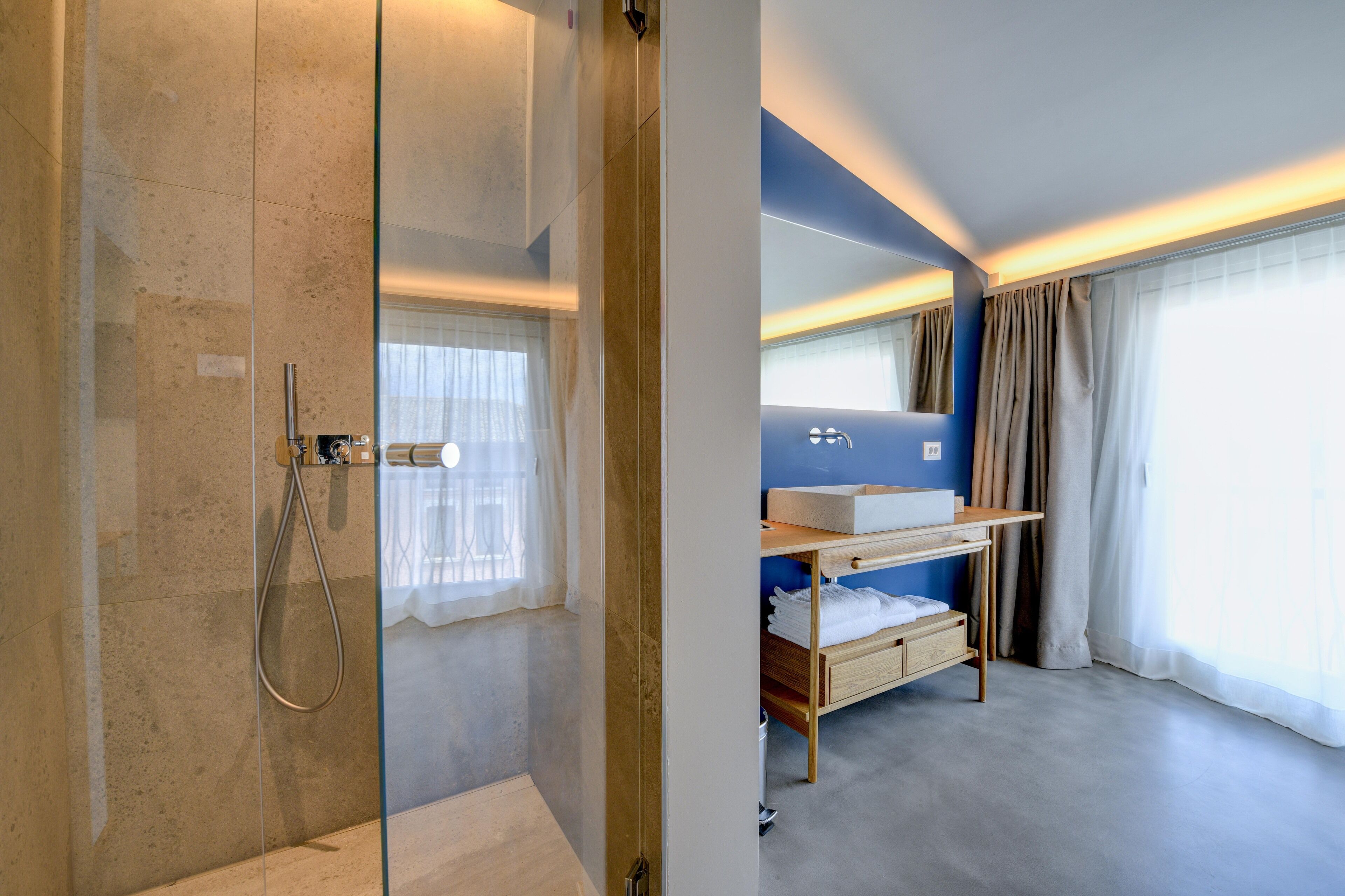 A modern bathroom with a glass shower enclosure, a wooden vanity with a sink, and a built-in bench.