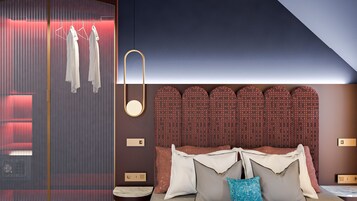 A modern bedroom with a large bed, a wardrobe with hanging clothes, and a unique headboard design.