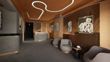 A modern hotel lobby with a reception desk, seating area, and artwork on the walls.
