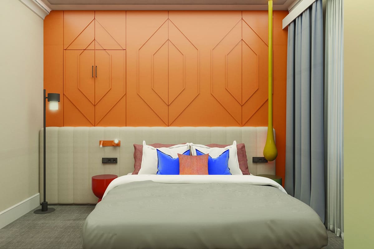 Habitación de hotel con cama, mesita de noche, lámpara y pared con diseños geométricos.