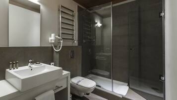 A modern bathroom with a glass-enclosed shower, a white sink, and a toilet.