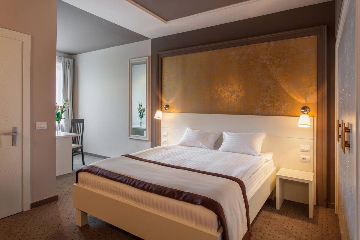 Habitación de hotel con una cama grande, mesitas de noche y un cabecero con lámparas fijadas a la pared.