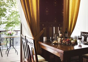 A dining area with a wooden table set for a meal, featuring candles, a bottle of wine, and a glass of red wine.