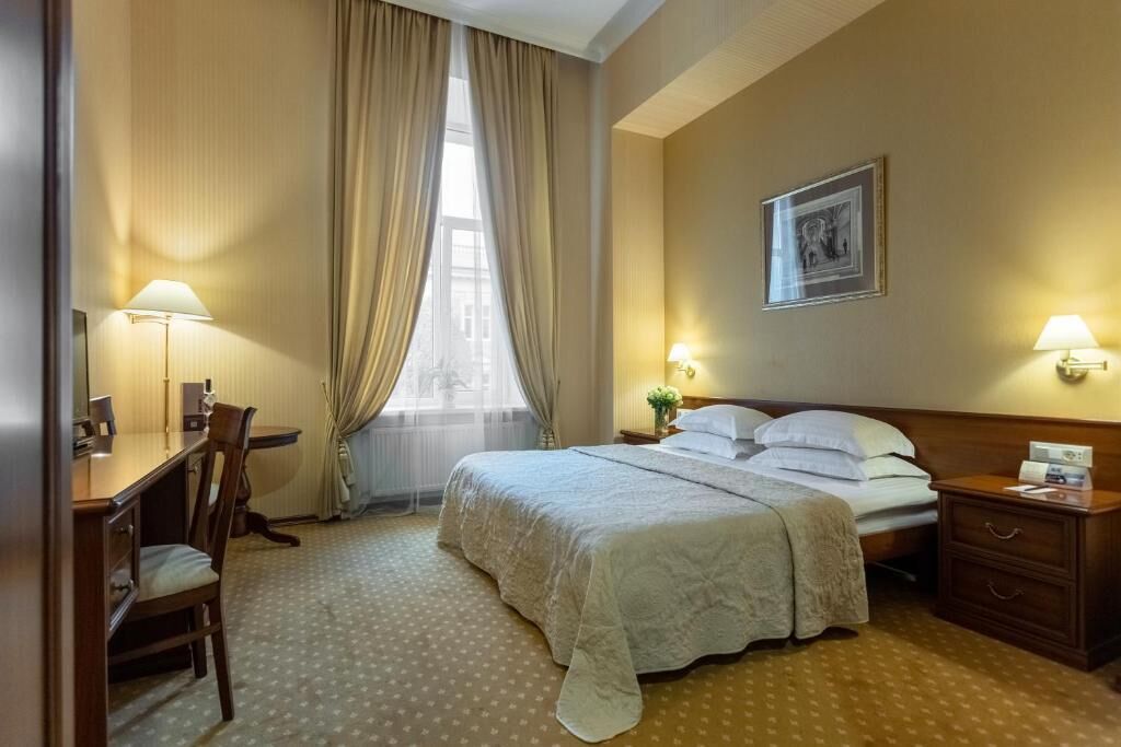 Une chambre d’hôtel comprenant un lit, des tables de chevet, un bureau et une chaise.