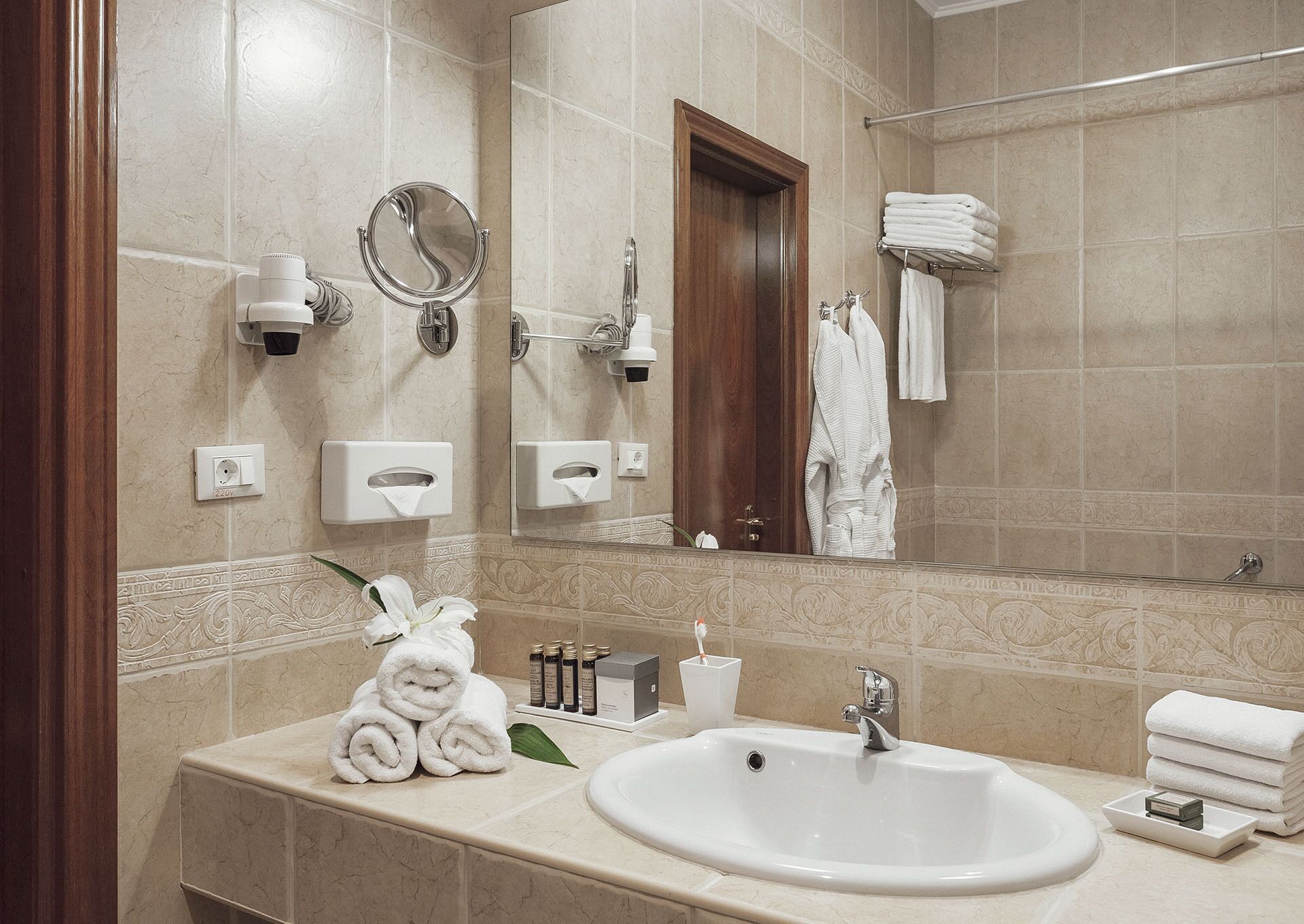 Un baño con lavamanos, espejo, toallero y artículos de aseo.