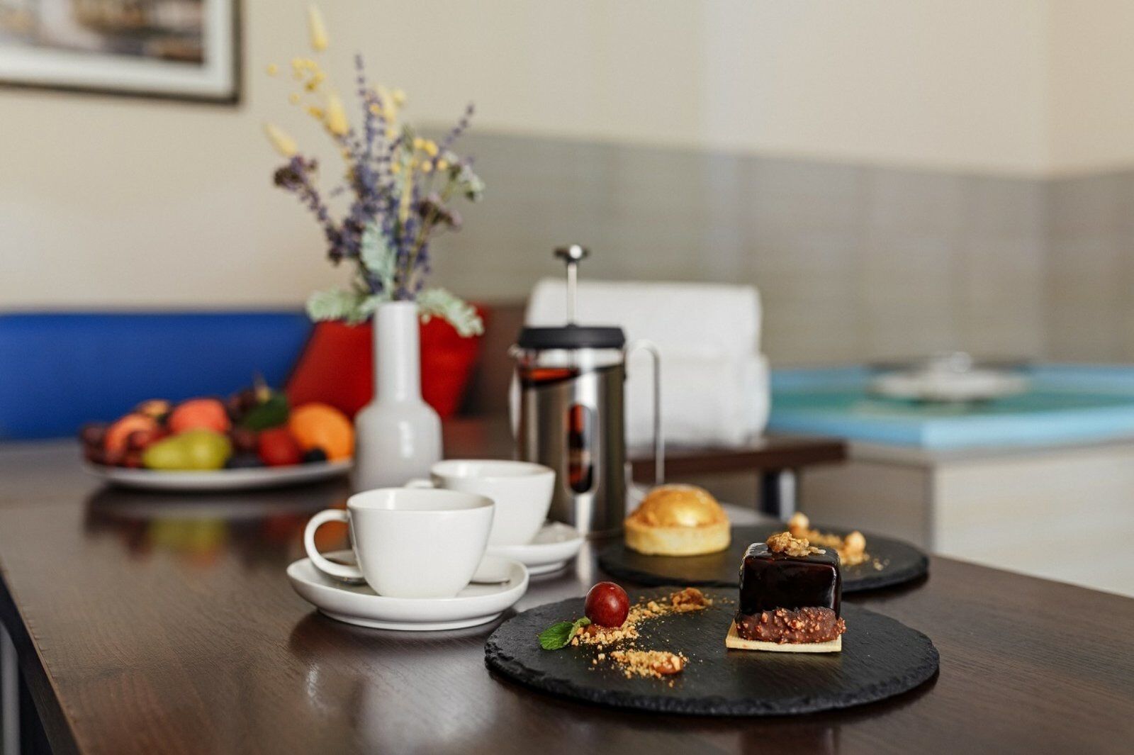 A breakfast setup with coffee, pastries, and fruits on a wooden table.