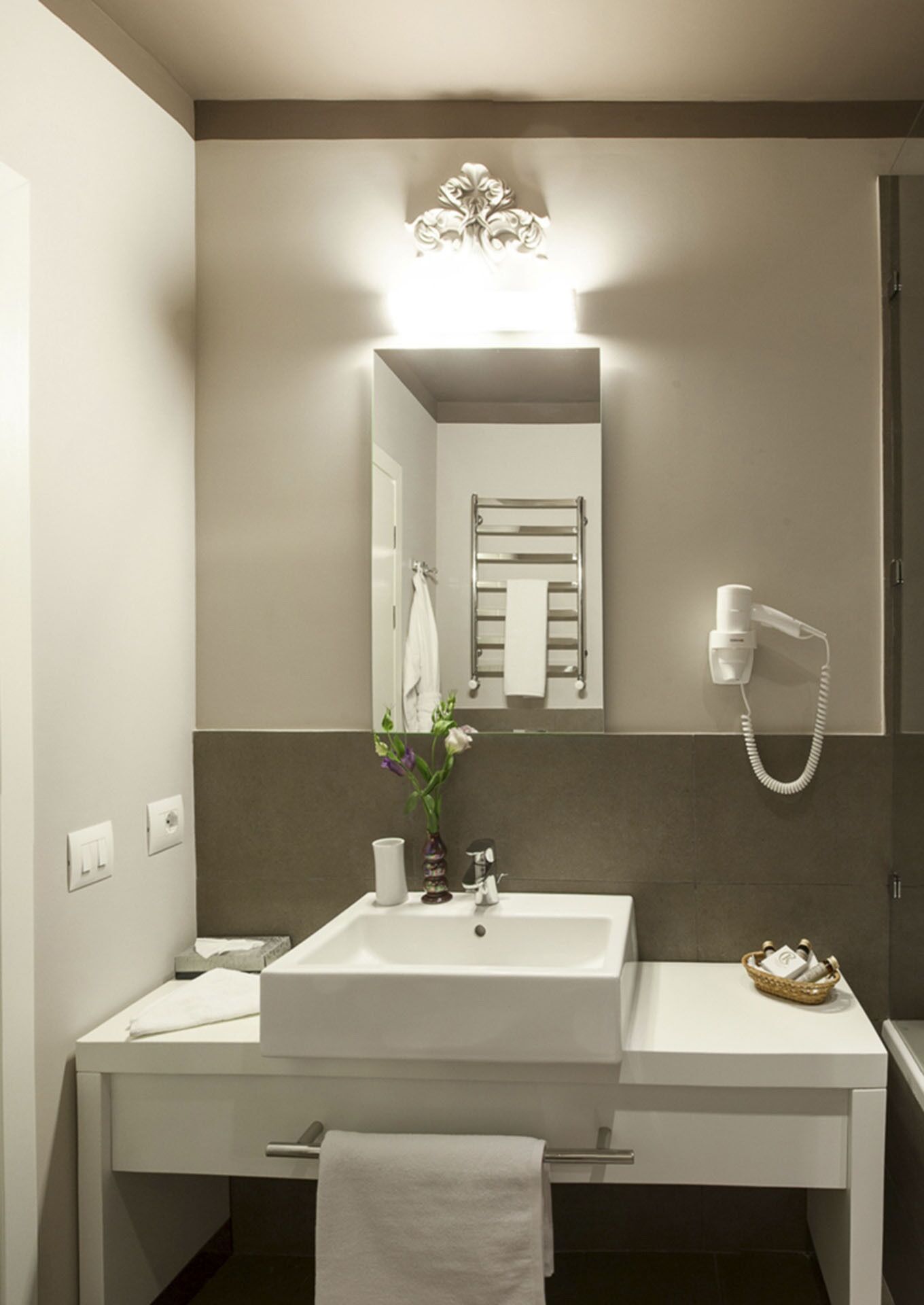 A modern bathroom with a white sink, mirror, and towel rack.