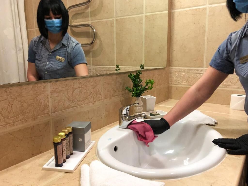A hotel bathroom with a sink, a mirror, a towel, and toiletries on the counter.