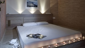 Quarto moderno com uma cama grande, um quadro na parede e uma série de velas ao longo da borda da cama.