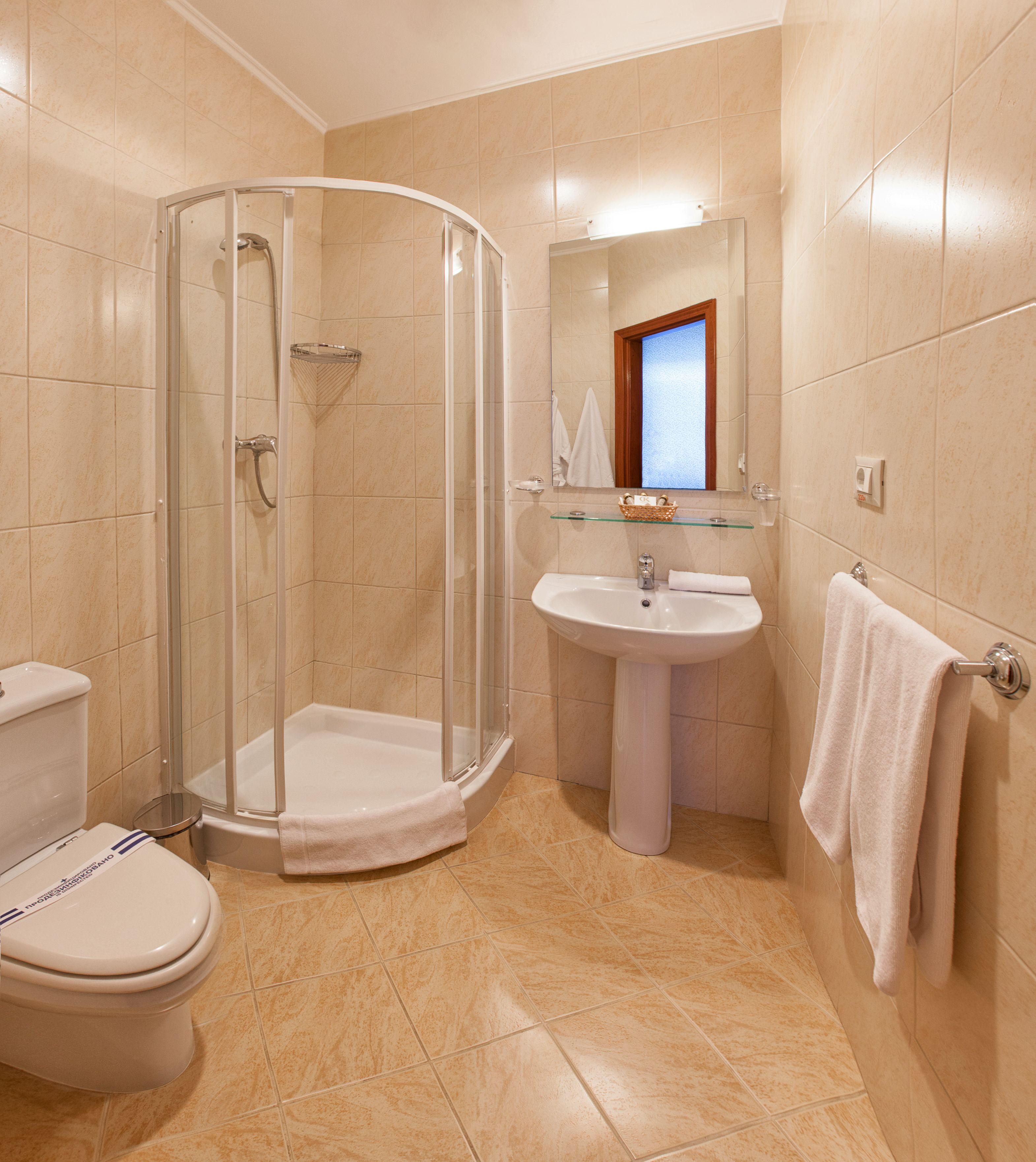 A bathroom with a glass shower enclosure, a pedestal sink, and a toilet.