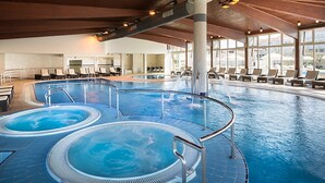 Une grande piscine intérieure dotée de plusieurs bains à remous et d’espaces de détente.