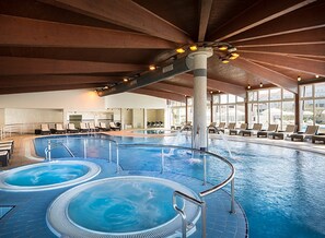 Een binnenzwembad, een buitenzwembad en parasols bij het zwembad